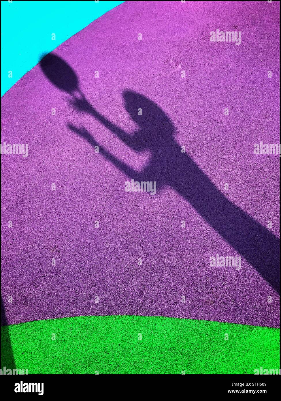 La sombra de un niño que está a punto de agarrar una pelota, es capturada en el fondo de los coloridos suelos blandos de un playground para niños. Una imagen con múltiples usos. Foto © COLIN HOSKINS. Foto de stock