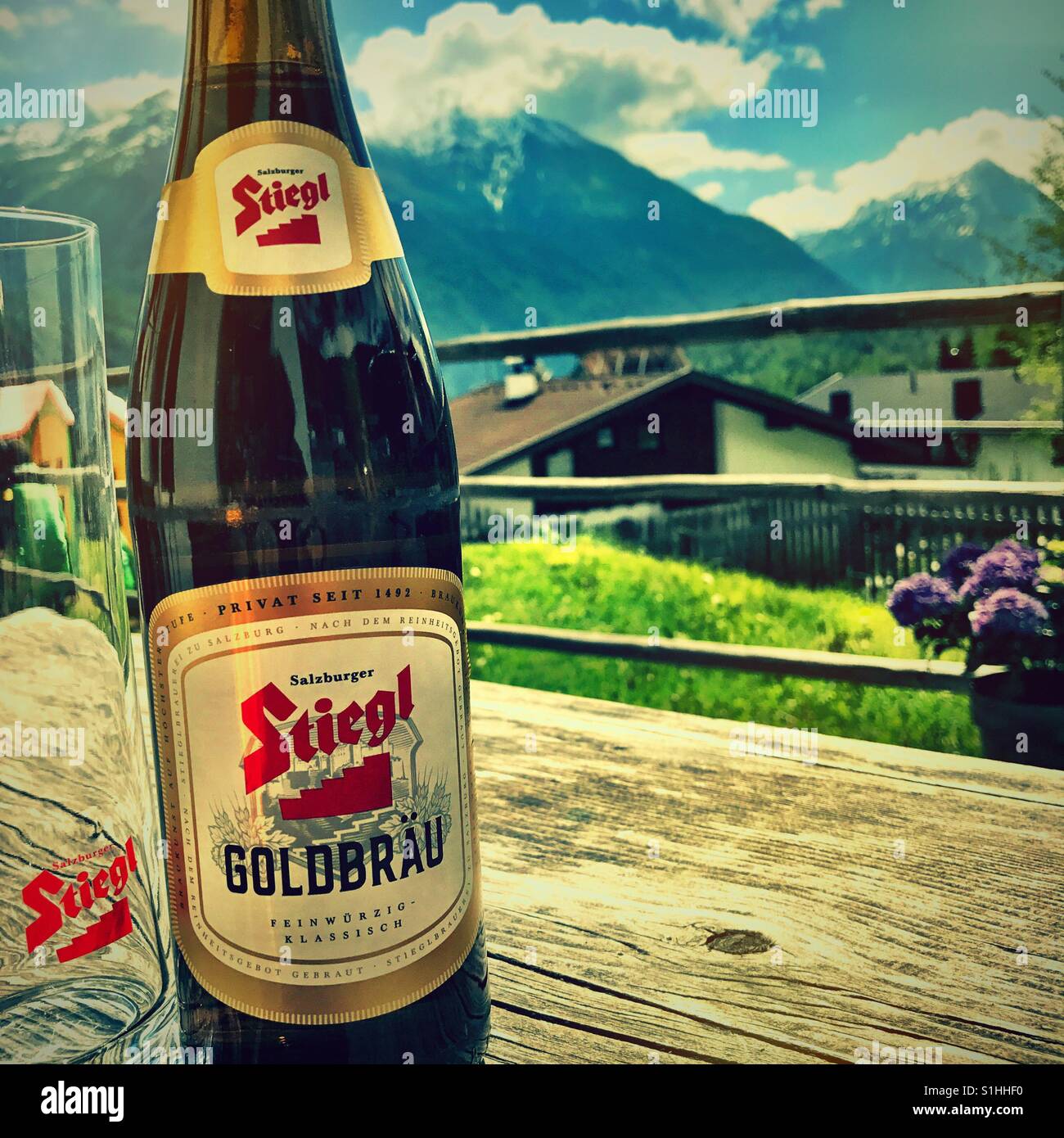 Cerveza Nacional de Austria, Stiegl descansando sobre una mesa de madera con un telón de fondo de las montañas suizas Foto de stock