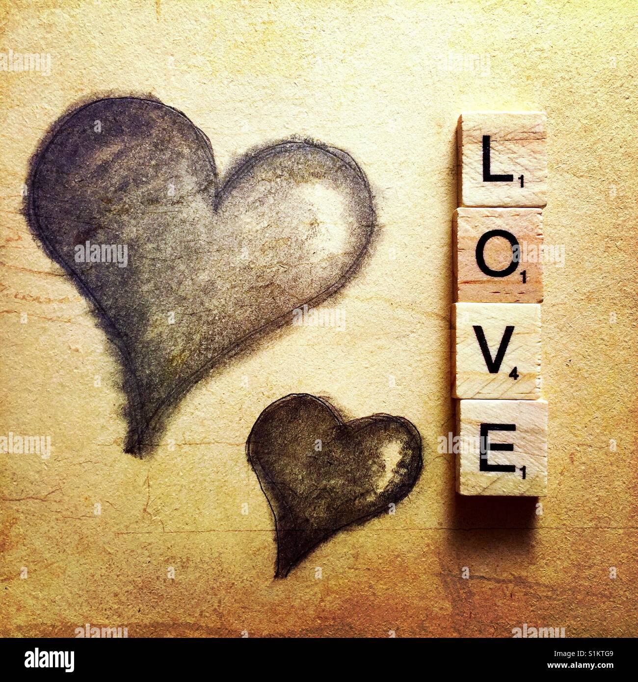 Un simple dibujo a lápiz de dos corazones y la palabra amor escrito con letras de madera Foto de stock