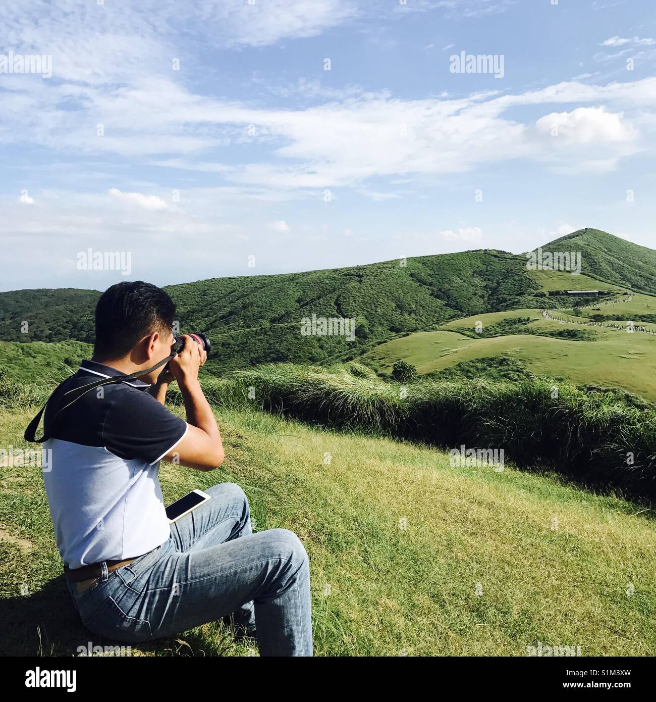 Un amante de la fotografía toma una foto de la hierba hills Foto de stock