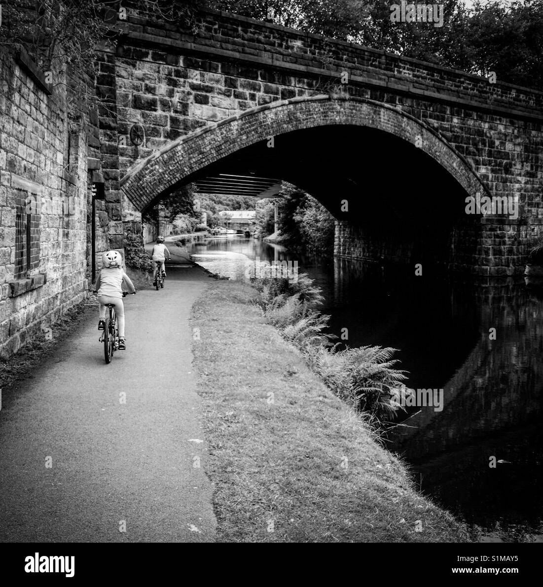 Dos niños andando en bicicleta en el Rochdale canal cerca de Elland, West Yorkshire. Foto de stock