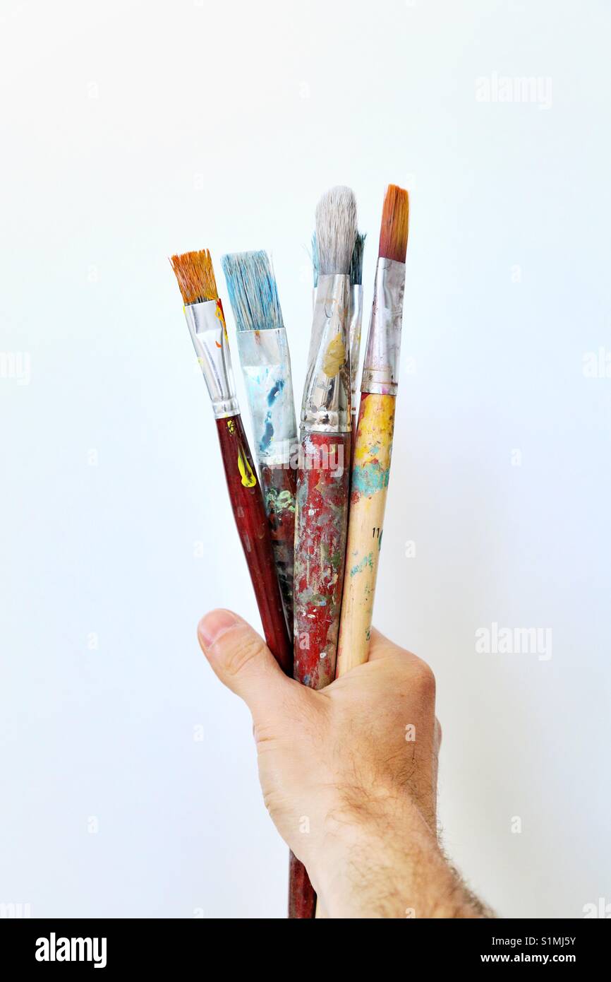 Una mano sosteniendo pinceles sucios Fotografía de stock - Alamy