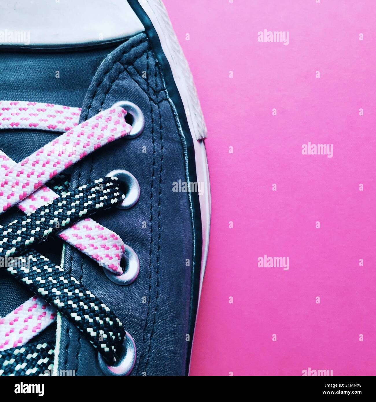 Detalle de una foto de una mujer con el funky de de zapatillas converse un fondo color rosa Fotografía de stock -