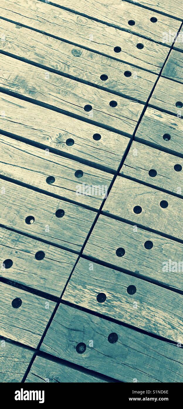 Patrón formado por tablones de madera, con agujeros, utilizado como revestimiento de suelo Foto de stock