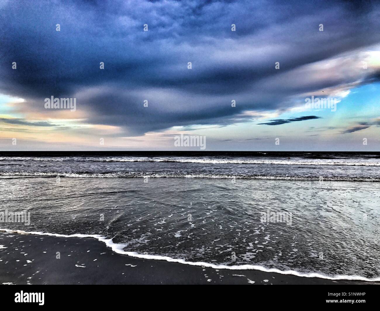 La orilla del mar con dramáticas nubes al atardecer Foto de stock
