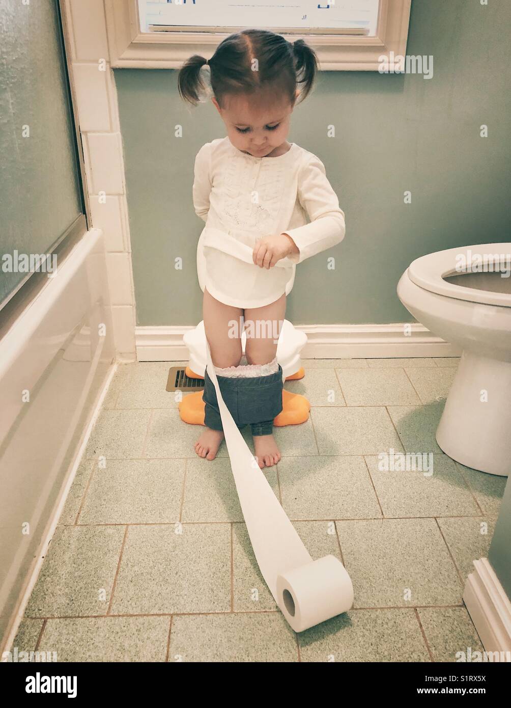 Habitat lamentar Multiplicación Niña de pie jugando con papel higiénico mientras entrena en el potty  Fotografía de stock - Alamy
