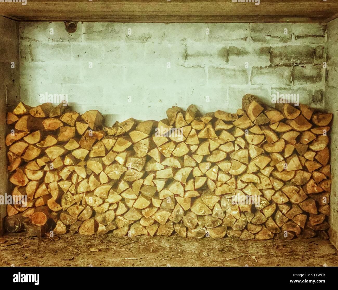 Registros de leña apilados en una sala de piedra cemento Foto de stock