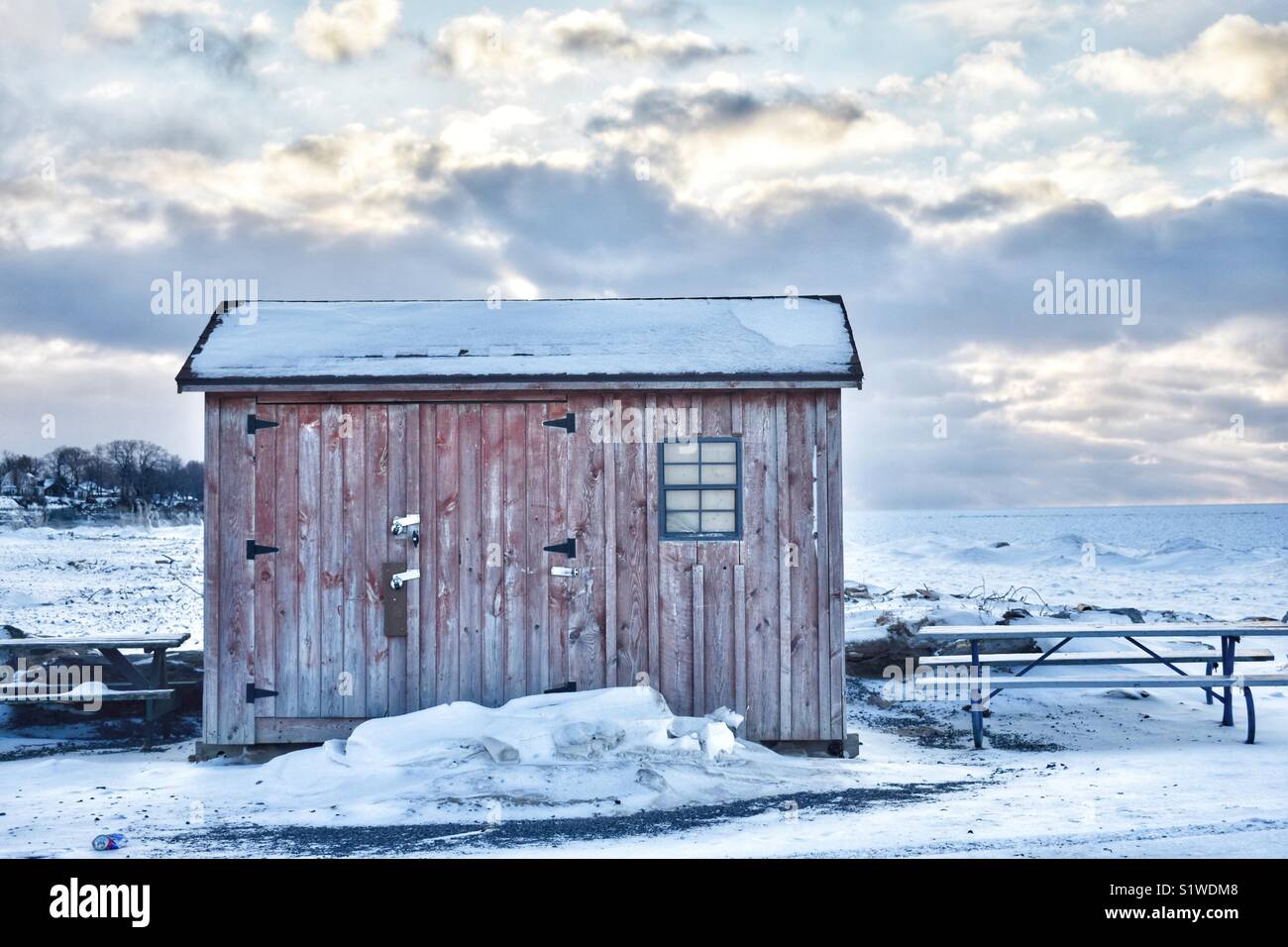 Pequeña cabaña sobre el lago nevado Foto de stock