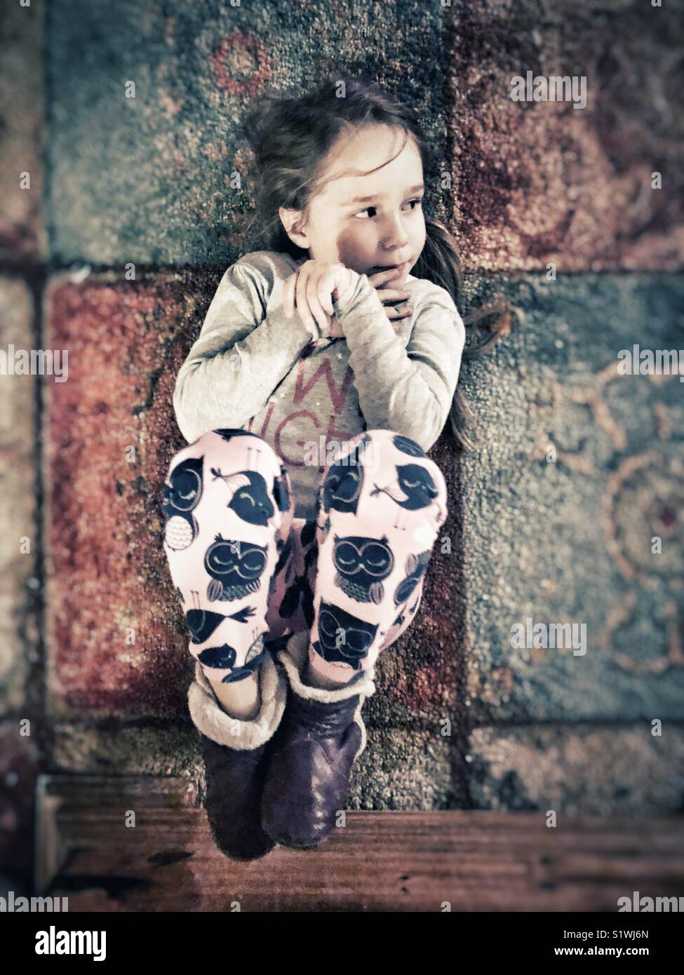 Niña de 5 años vistiendo pijama acomodado en posición fetal sobre la  alfombra mirando hacia el lado Fotografía de stock - Alamy