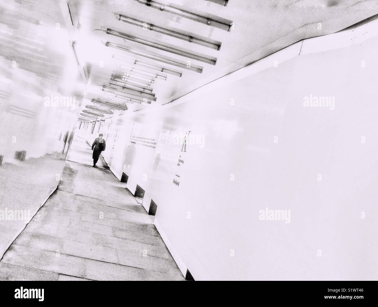 Una sola figura caminando por un pasillo blanco Foto de stock