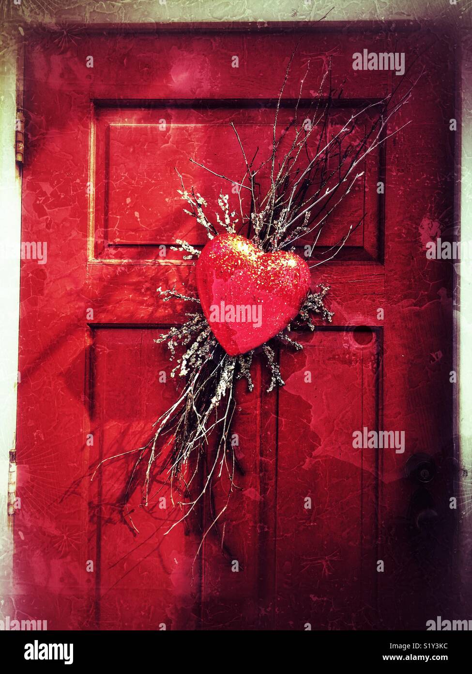 Glitter corazón rojo corona en puerta roja Foto de stock