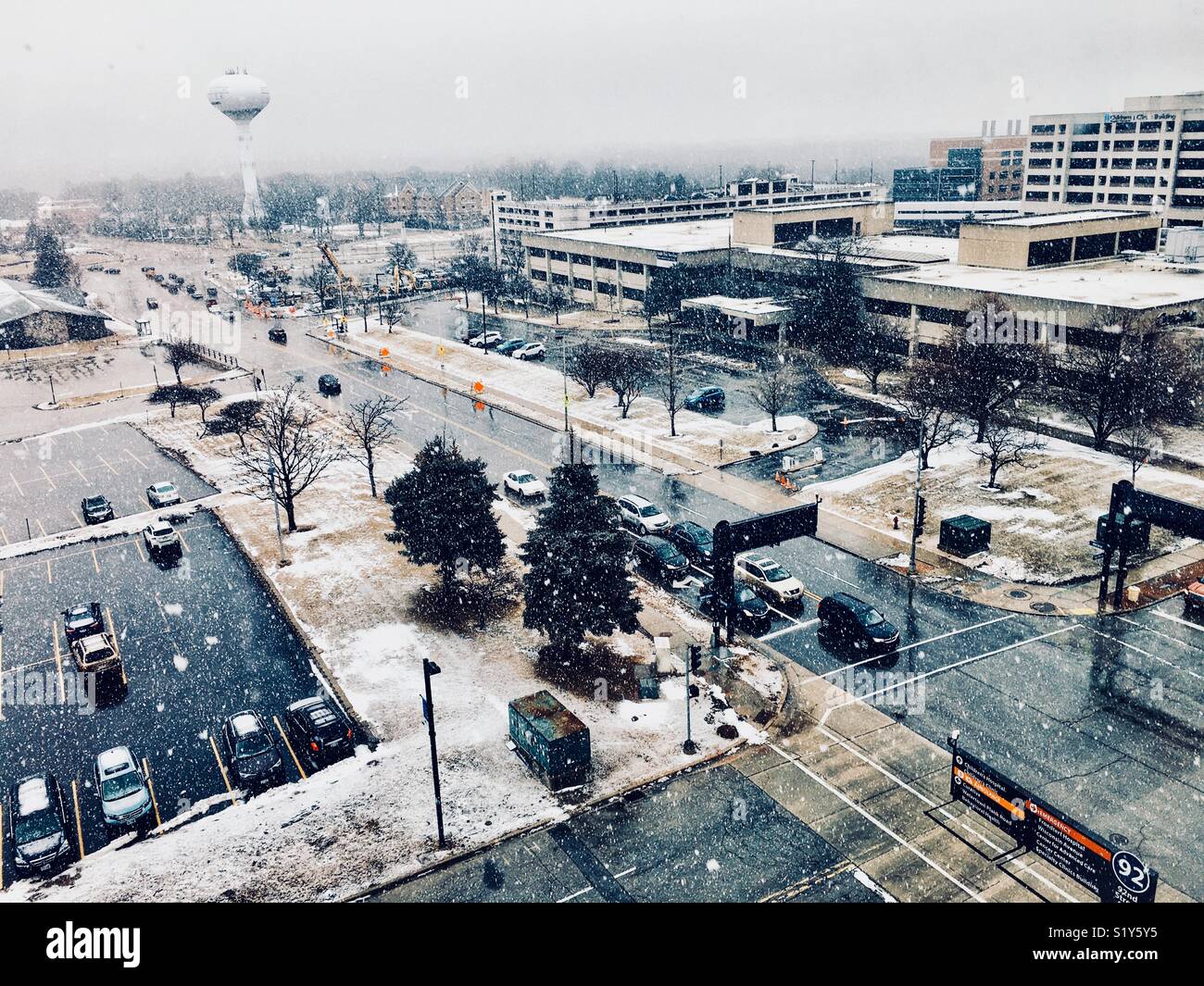 Ver por encima del nivel de la calle de automóviles circulando hacia el hospital como la nieve cae Foto de stock