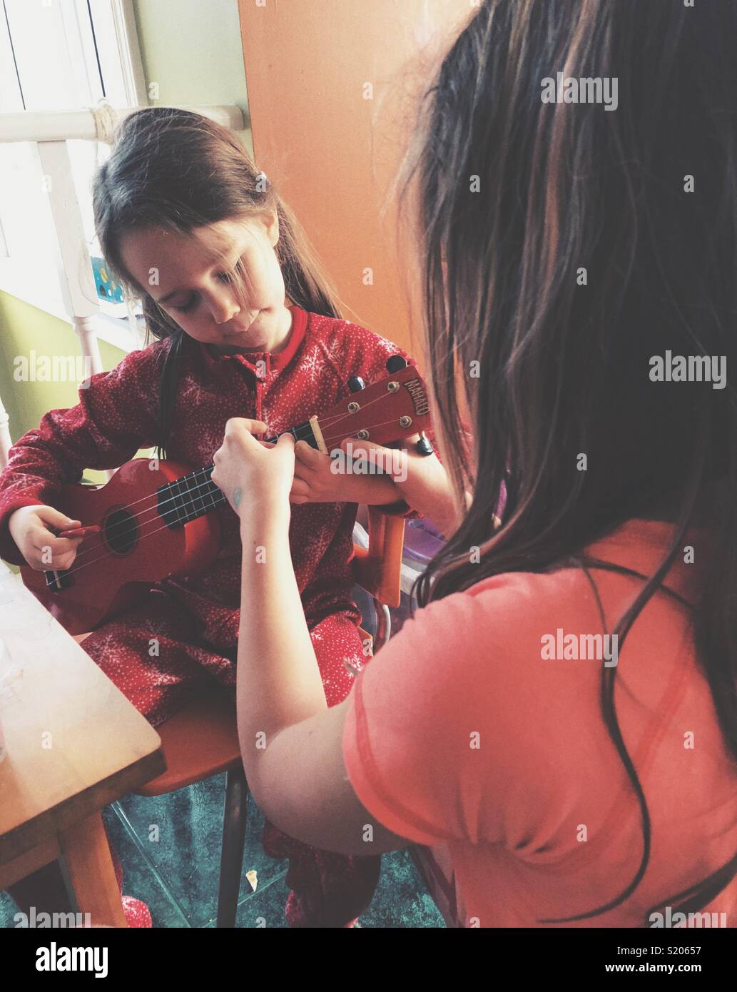 Big Sister hermanita enseñar cómo jugar a ukulele Foto de stock