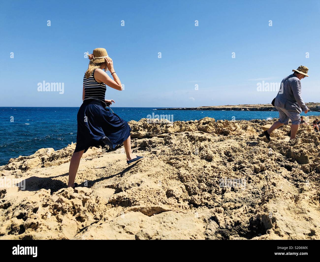 Un hombre y una mujer caminando sobre rocas en Chipre Foto de stock