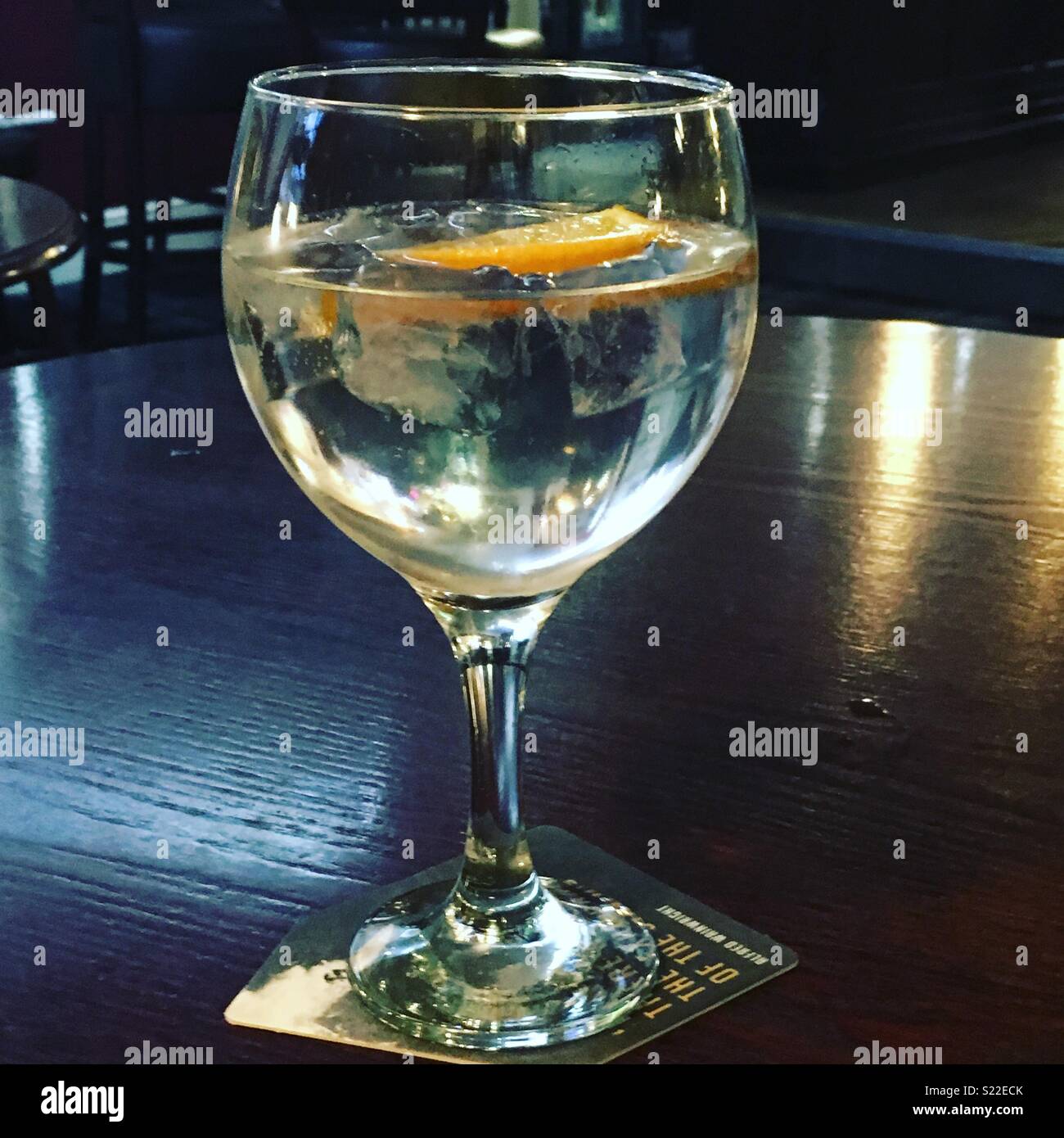 Un gran vidrio de gin tonic con hielo y una rodaja de naranja Foto de stock