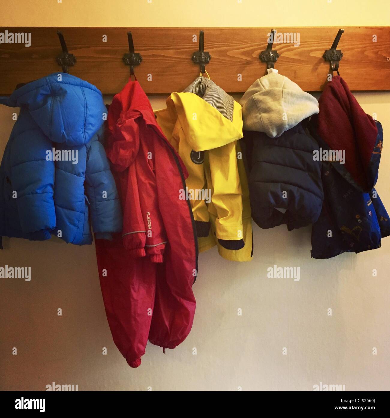 Fila de niño abrigos coloridos en el perchero Foto de stock