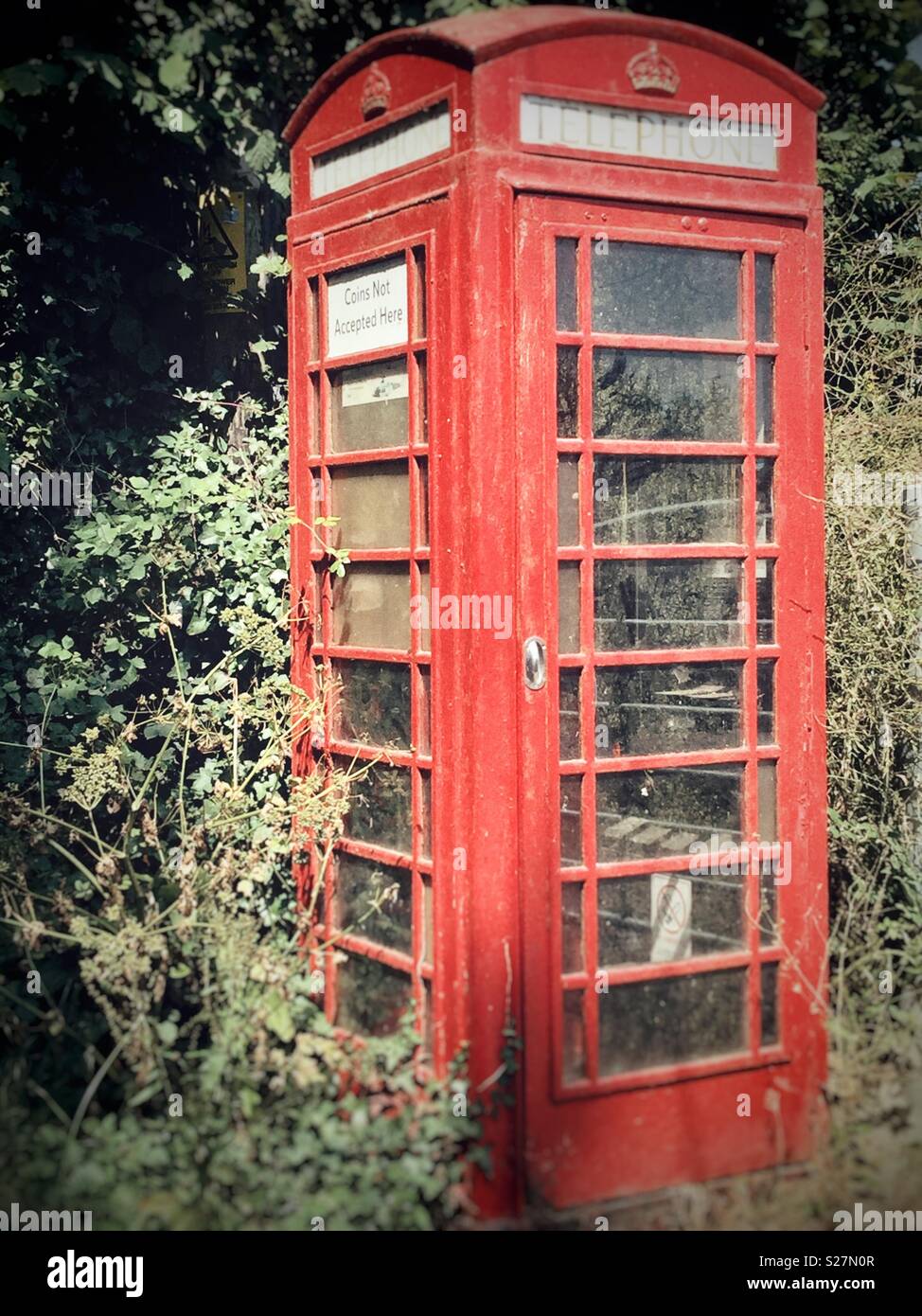 Antiguo cuadro Teléfono Rojo siendo reclamados por la naturaleza Foto de stock