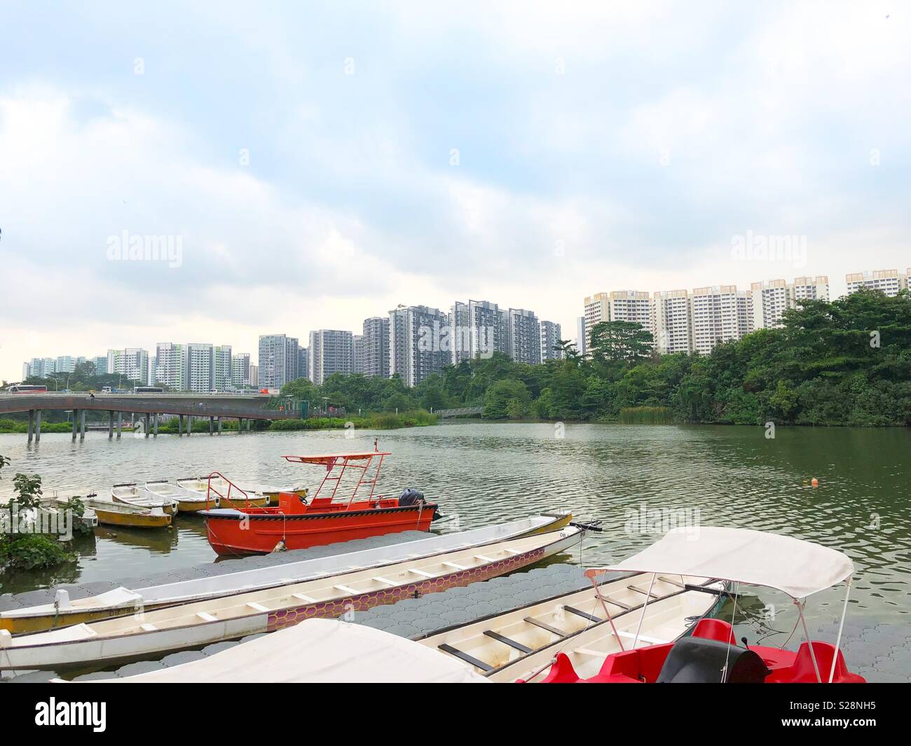 Barcos de pesca estacionada sobre un cuerpo de agua con apartamentos residenciales en el fondo Foto de stock