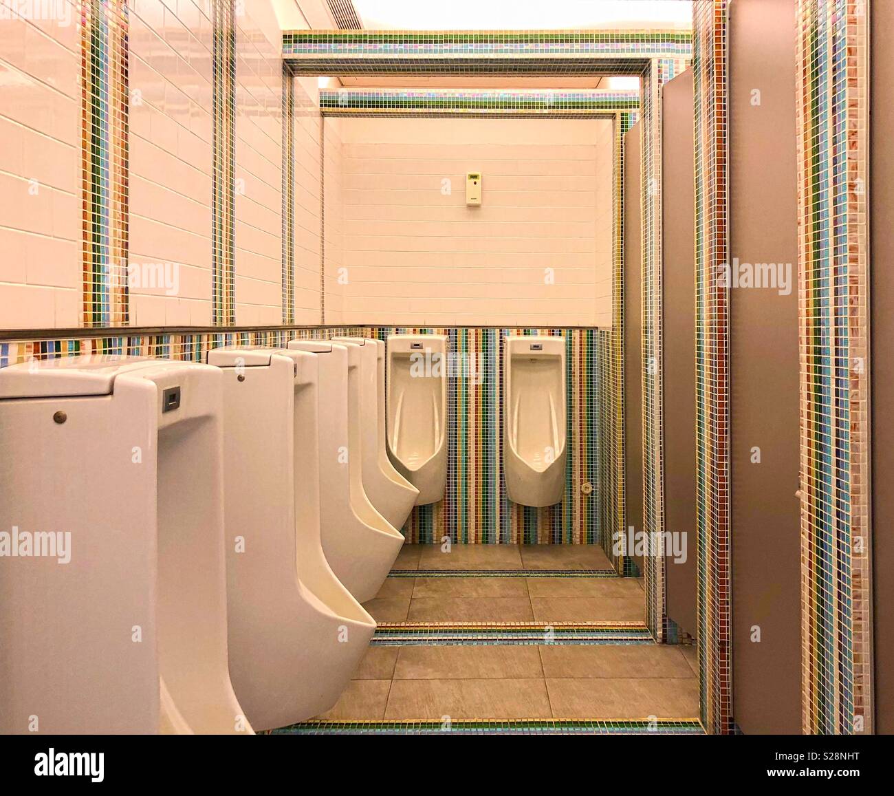 Hilera de urinarios en concepto retro wc masculinos con coloridos azulejos de cerámica antecedentes Foto de stock