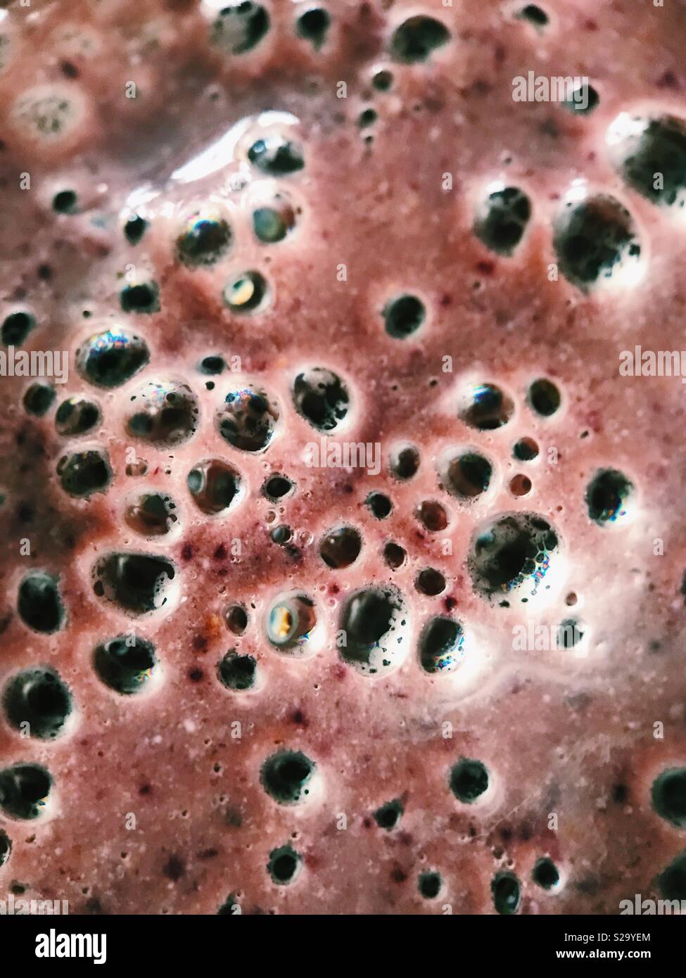 Macro de burbujas en la superficie de un arándano y cereza batido. Foto de stock