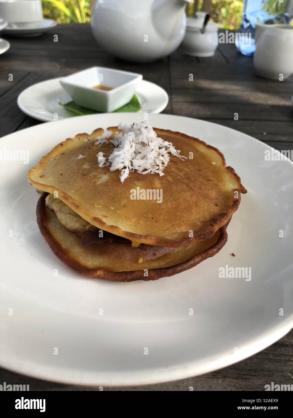 Una pila de panqueques de banana con coco afeitada en la parte superior Foto de stock