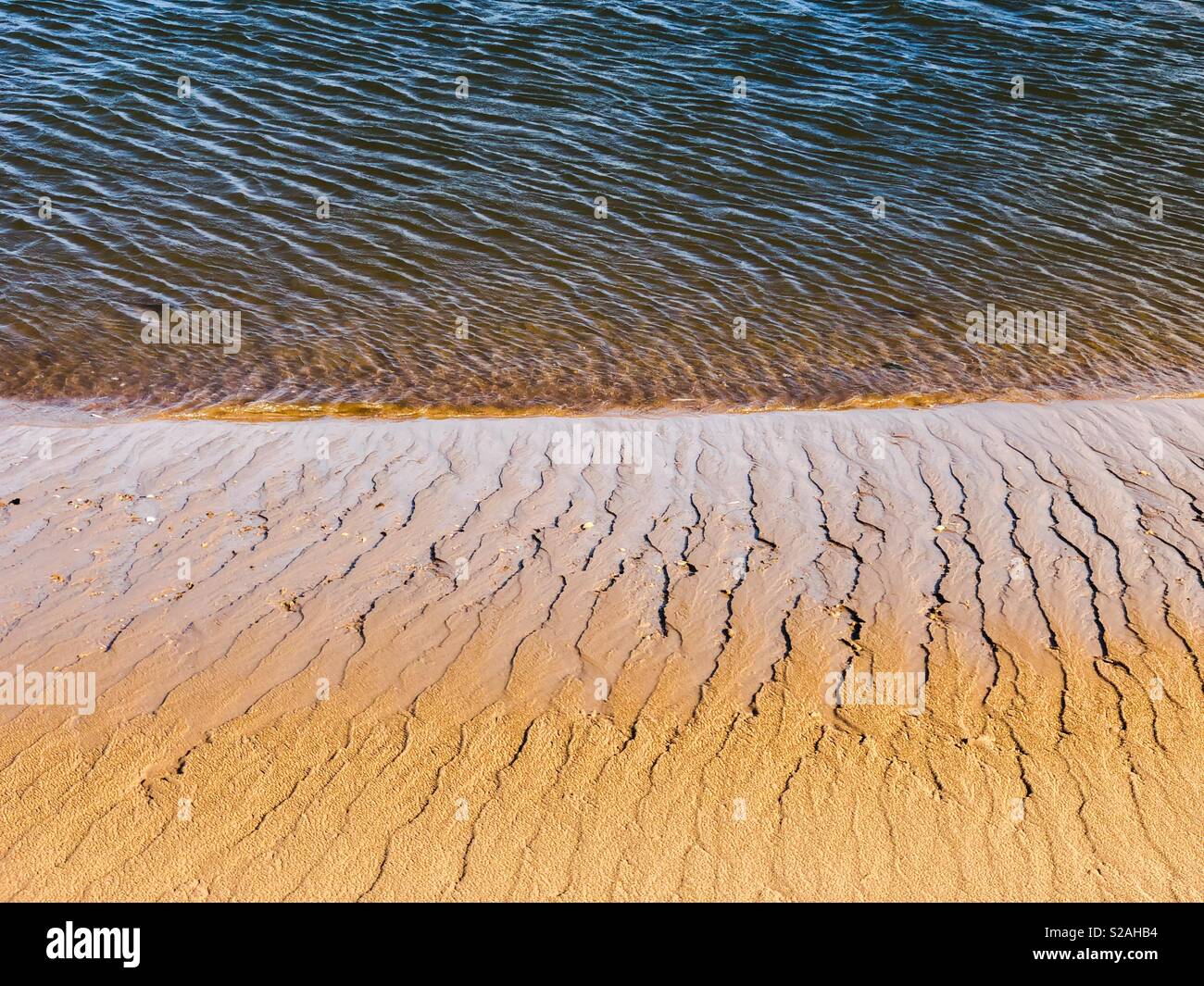 Línea de flotación donde el mar se encuentra con la arena dejando patrones abstractos Foto de stock
