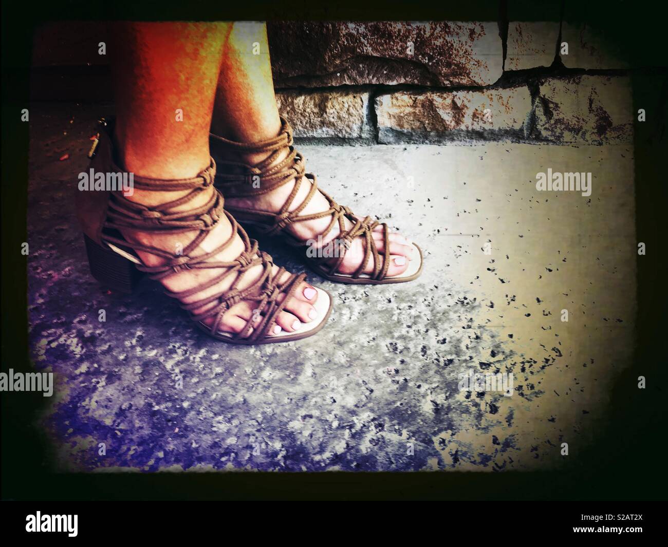 Mujer vistiendo ligero Dreamgirl tiras marrón sandalias de gladiador fuera en el patio, en los calurosos días de verano Foto de stock