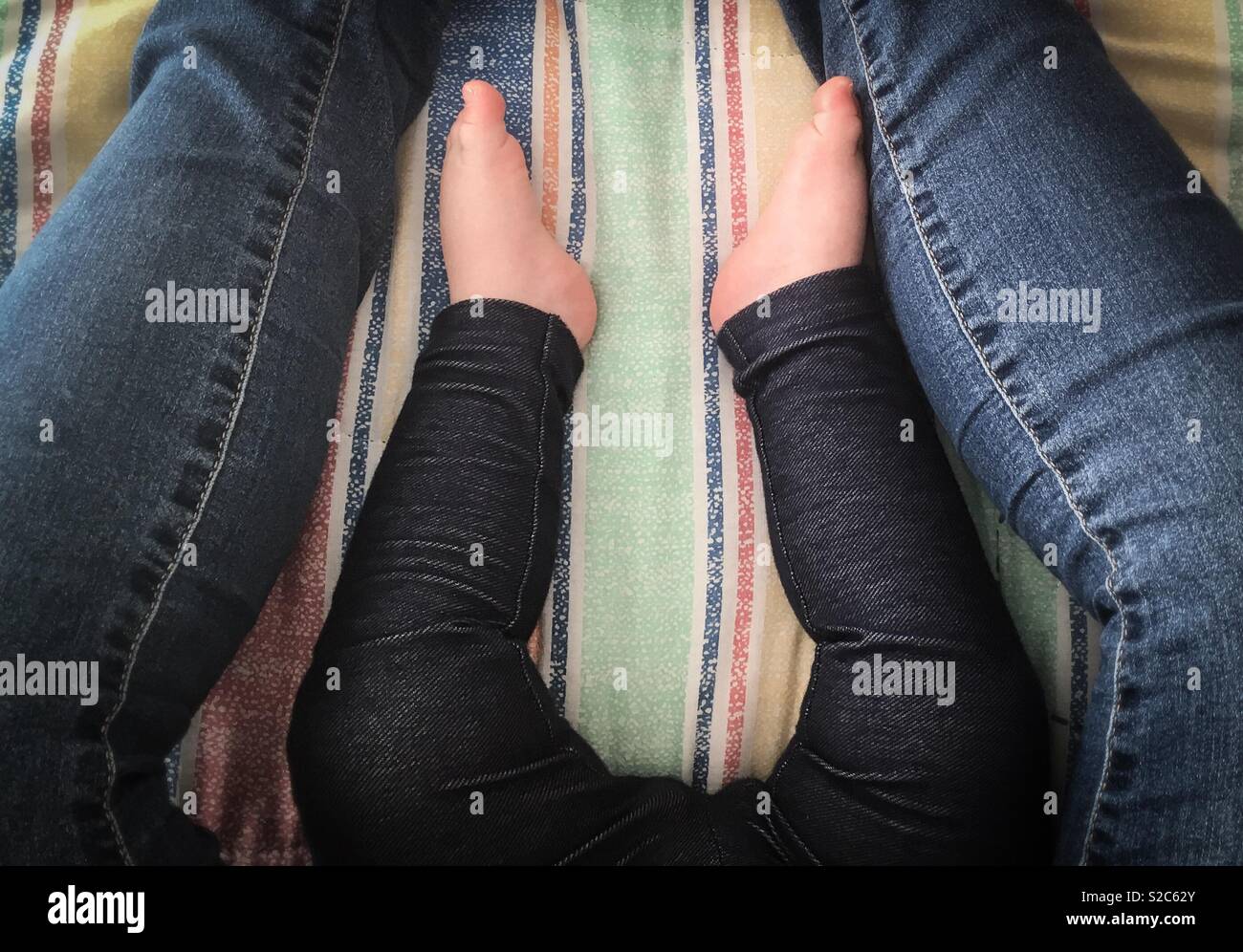 La mamá y el bebé se sientan juntos en jeans Foto de stock