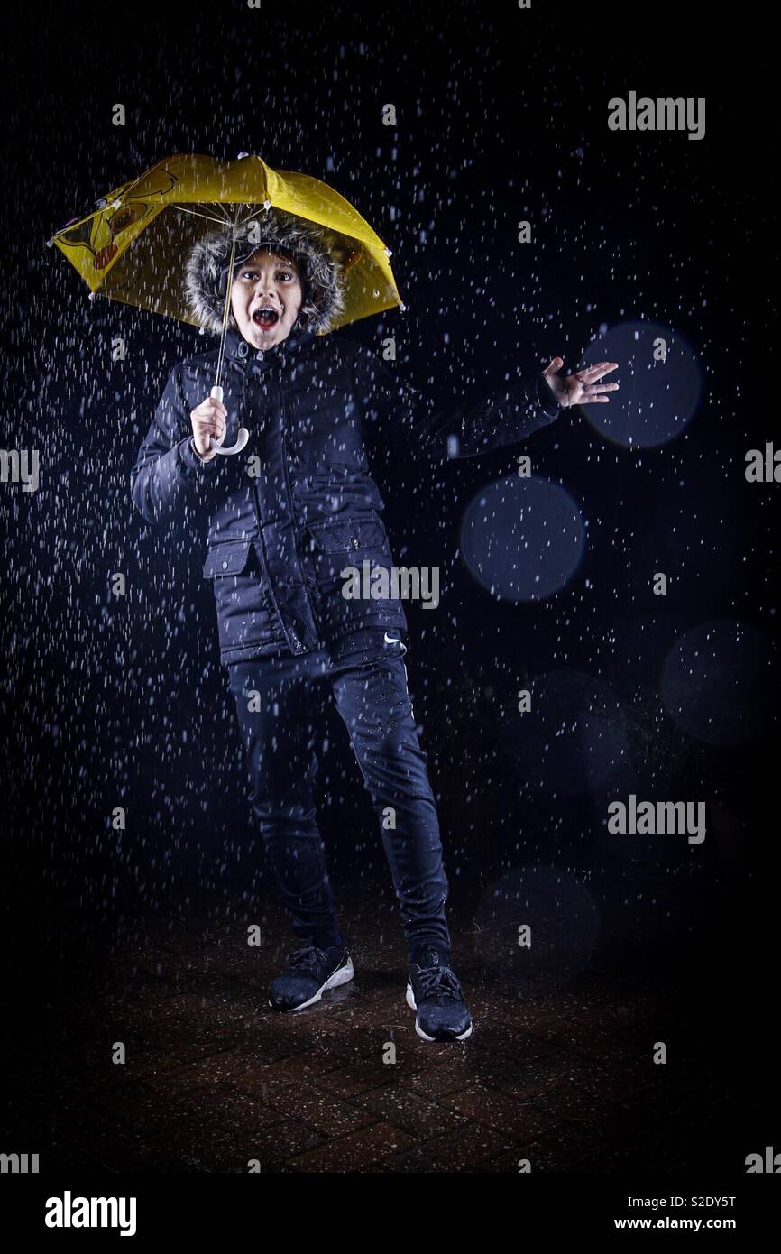 Cantando bajo la lluvia - joven con paraguas amarillo en la lluvia  Fotografía de stock - Alamy