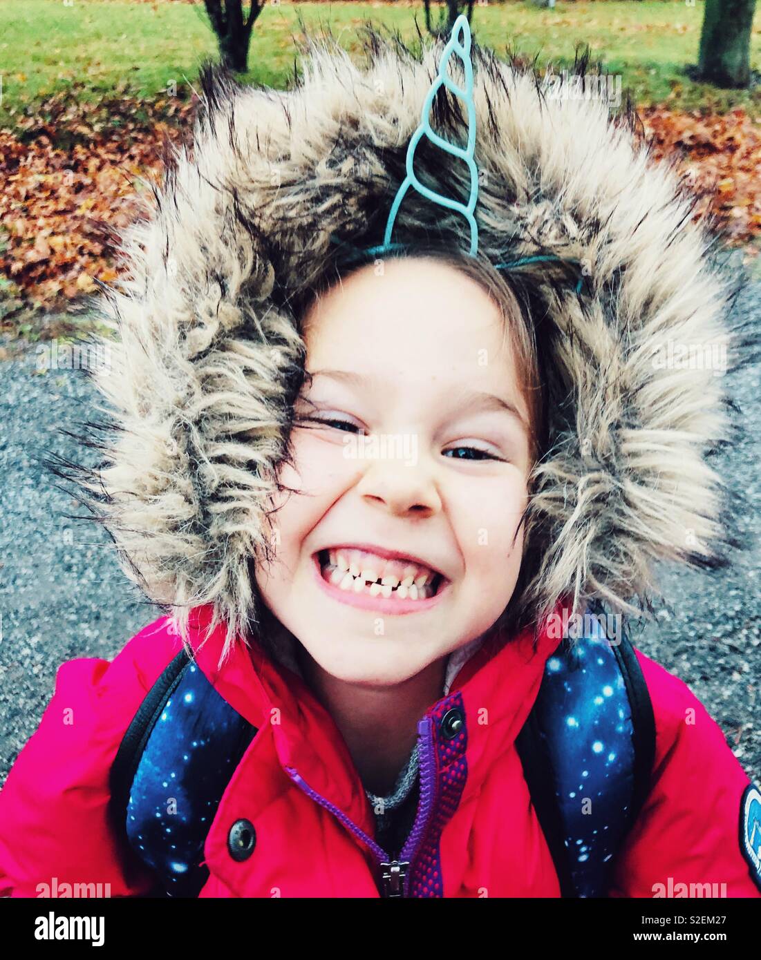 Retrato de una niña de 6 años de edad sonriente vistiendo cuerno de  unicornio y rosa diadema invierno chaqueta con capucha peluda Fotografía de  stock - Alamy