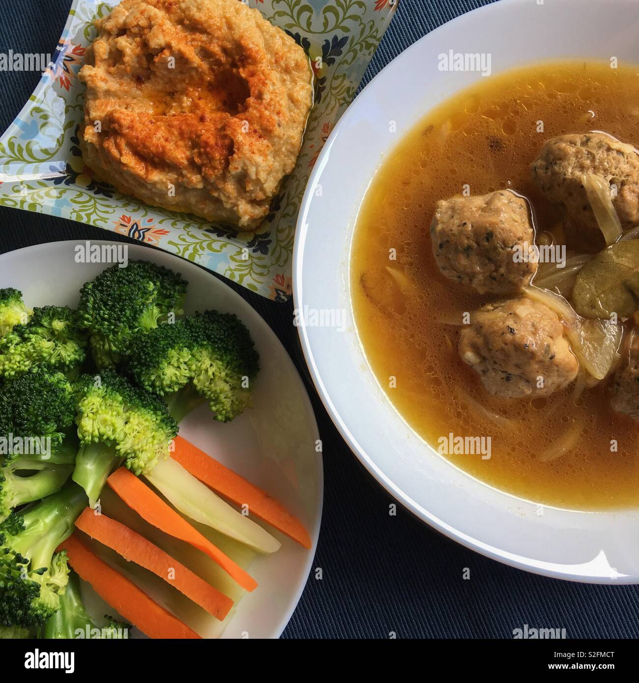 Abundante comida de pollo sopa de pelotas, vapor el brócoli y la zanahoria y humus. Foto de stock