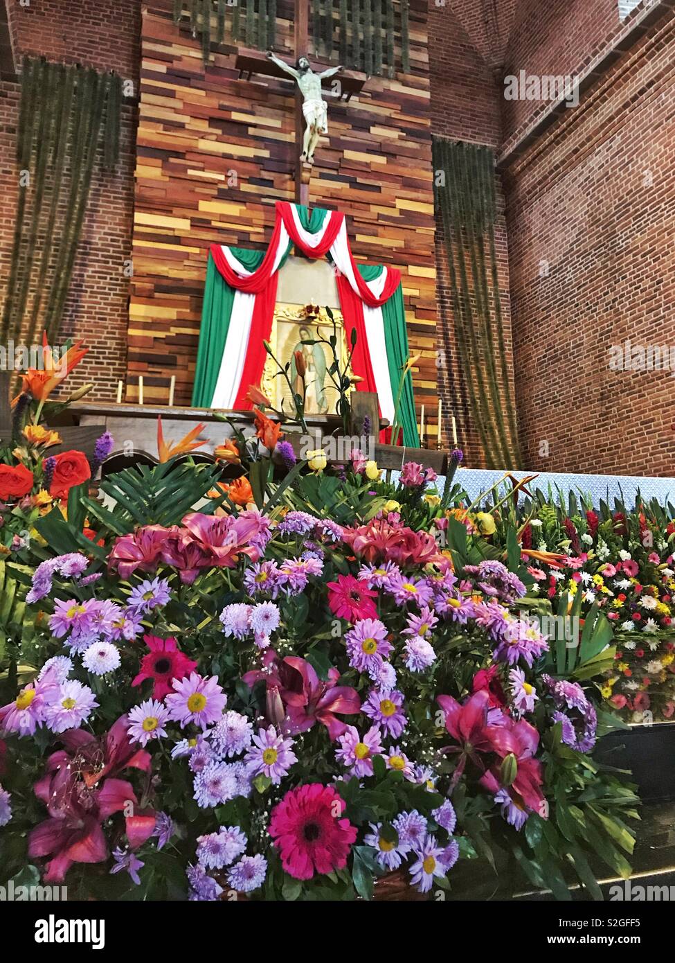 Una abundancia de flores y arreglos florales que decoran la parte frontal  del altar de la Iglesia de Nuestra Señora de Guadalupe durante un festival  en Tapalpa, México Fotografía de stock -