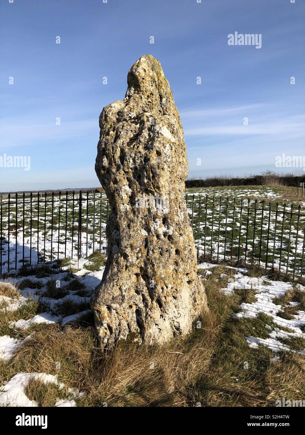 El rey piedra en el Rollright Stones en la nieve contra un cielo azul brillante. Foto de stock