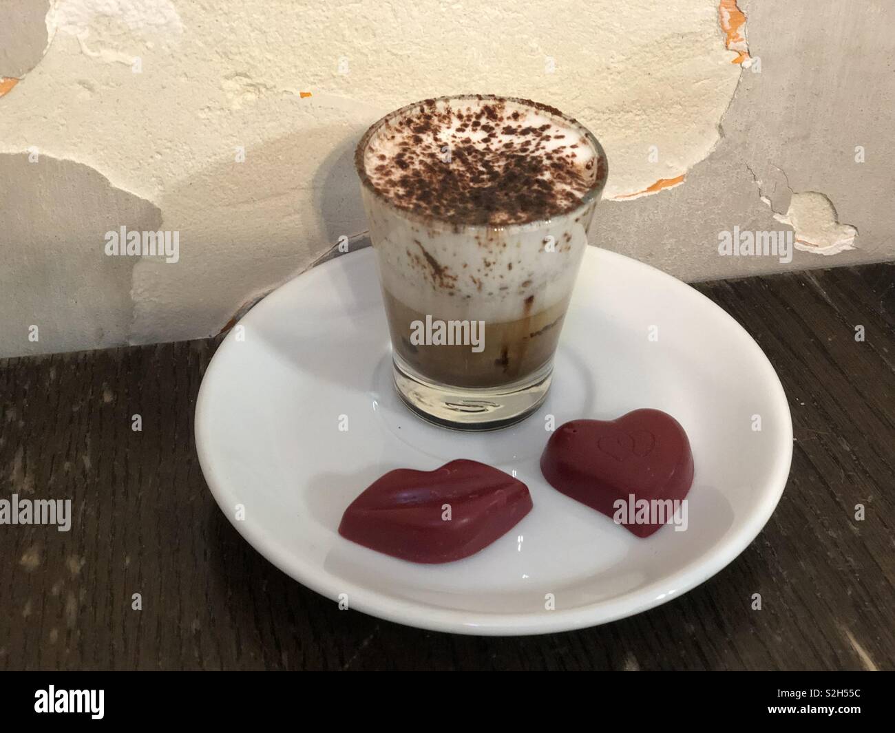 Celebrando el Día de San Valentín con un sabroso café espresso con leche y chocolates rojo Foto de stock
