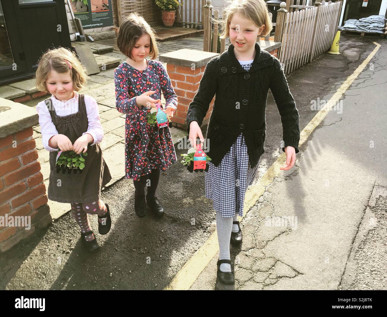 Niños, niños, niños, hermanas, jóvenes jardineros dejando un jardín central con las plántulas / bandejas de plantas que acaban de comprar comprado. Uk Foto de stock
