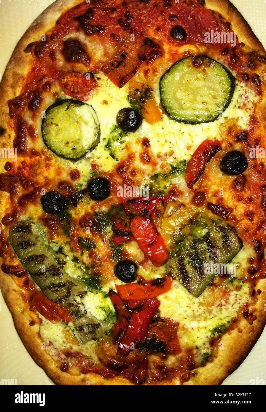Pizza sonriente. Imagen que representa una comida recién cocinado pizza mostrando una similitud con una cara sonriente. Foto de stock