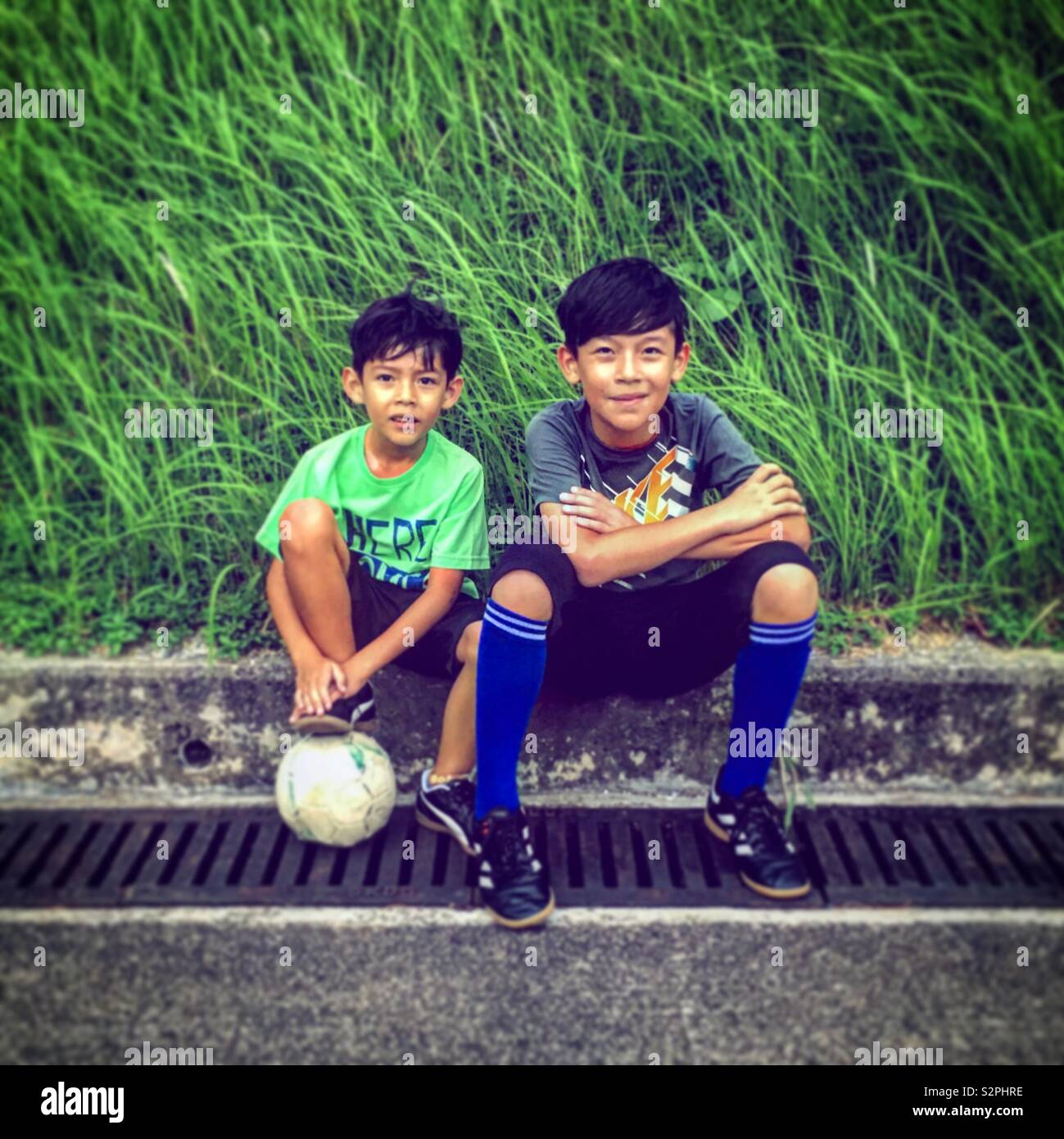 2 chicos asiáticos descansando después de un partido de fútbol Foto de stock