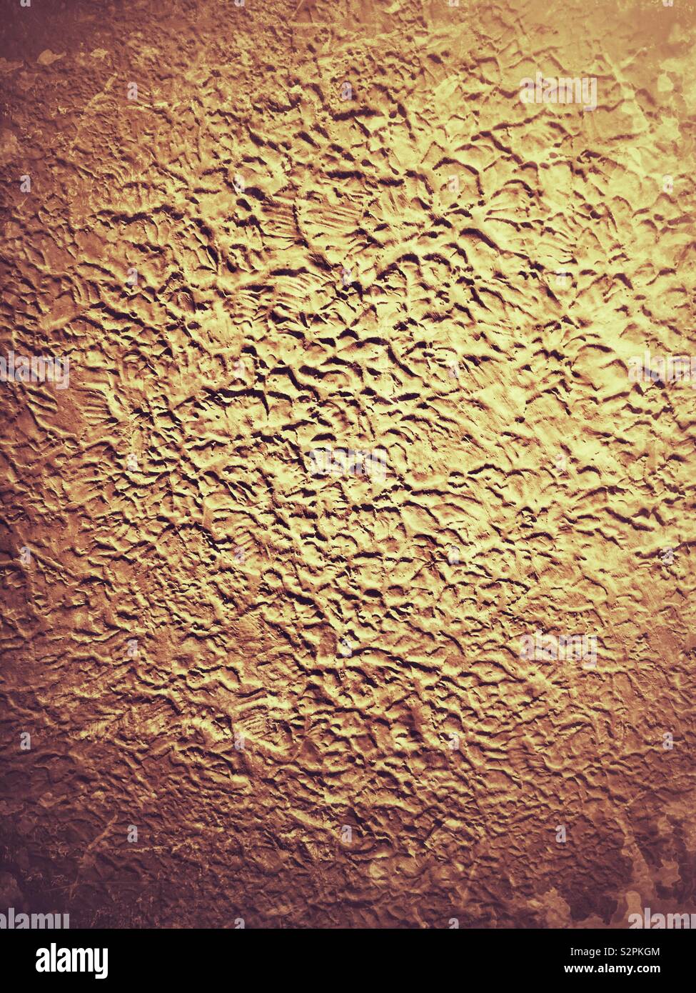 Stipple textura superficial sobre una antigua pared de estuco de cemento pintada de un color marrón dorado. Foto de stock