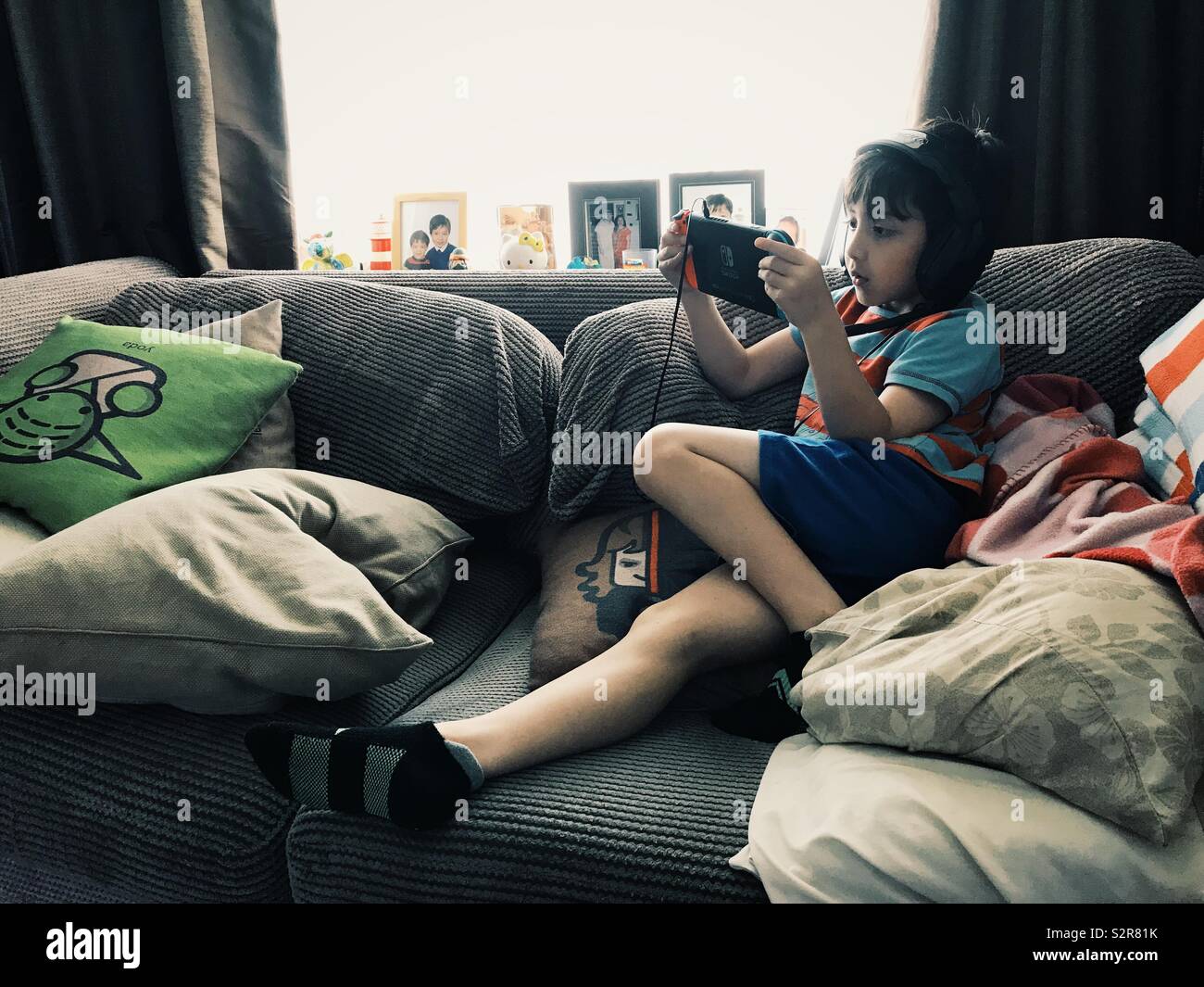 Un joven está sentado en un sofá jugando juegos de video en su computadora  de mano del interruptor de la consola de Nintendo Fotografía de stock -  Alamy