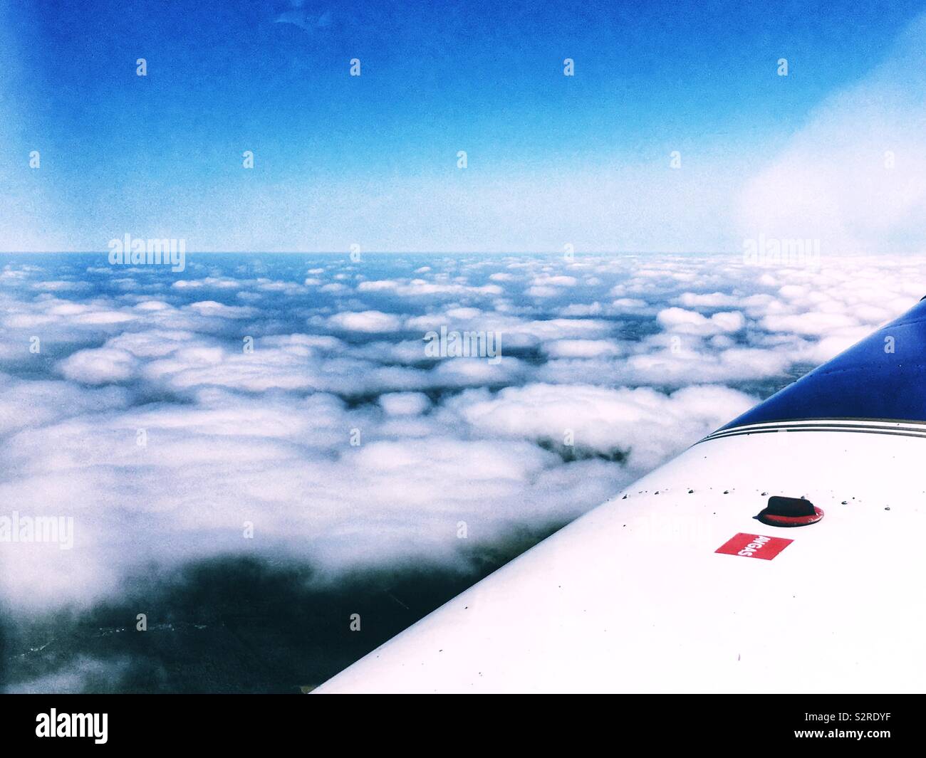 Mirando por la ventana de un avión ligero a la aleta y suelo a través de las nubes. Foto de stock