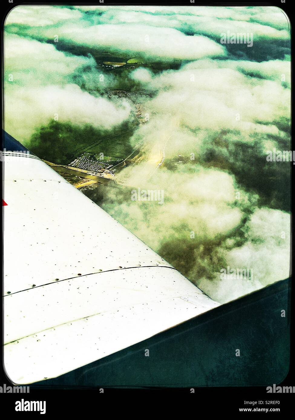 Mirando por la ventana de un avión ligero a la aleta, el cielo nublado y la tierra. Foto de stock