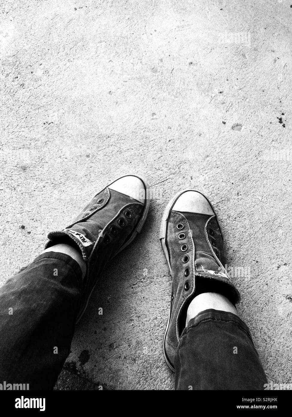 Persona vestida de viejos zapatos Converse All Star resistente sobre la  superficie del hormigón Fotografía de stock - Alamy