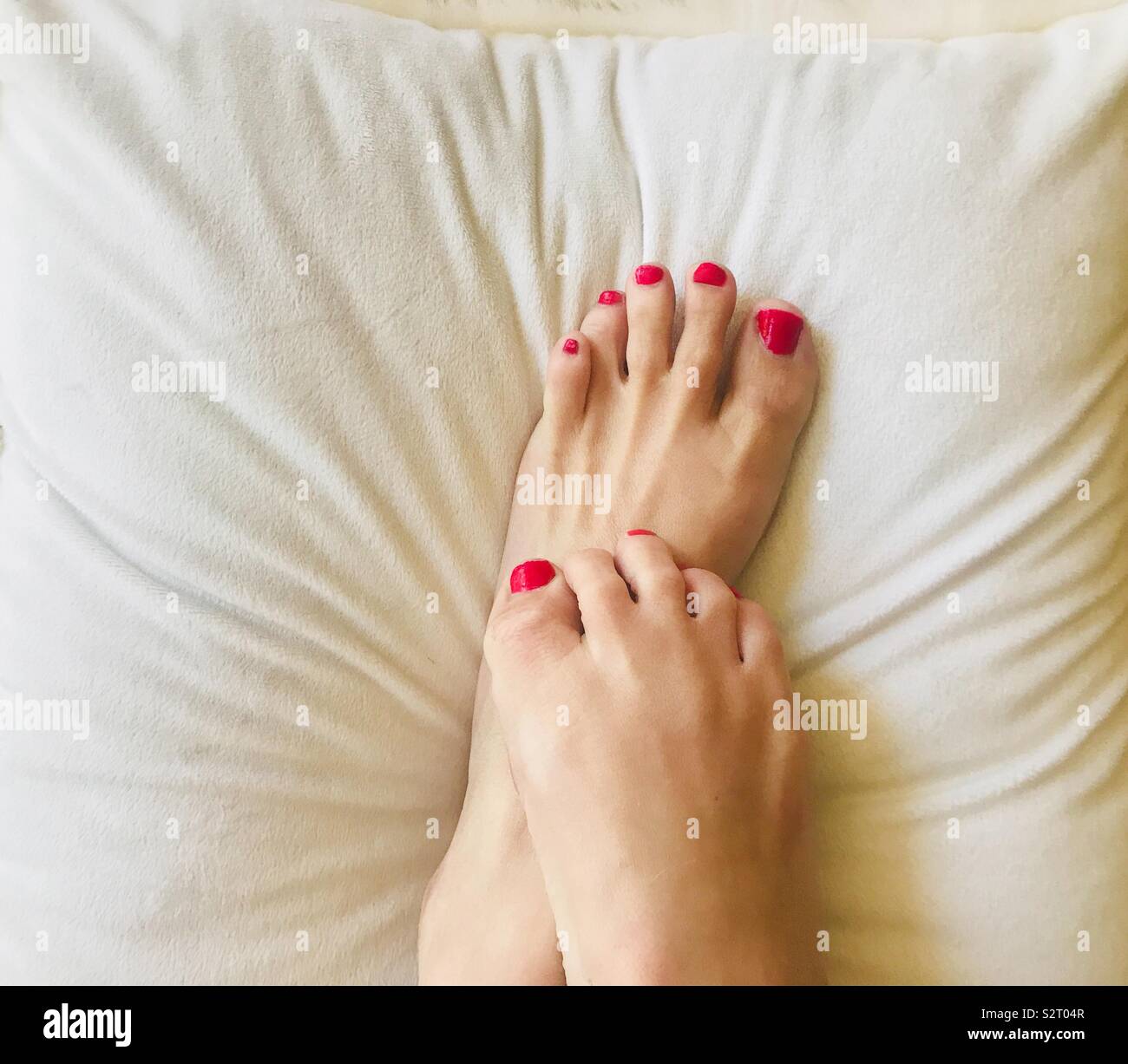 Una Hermosa Mujer Con Los Pies Pintados De Rojo Las Unas De Los Pies Sobre Una Almohada Suave Blanco Fotografia De Stock Alamy