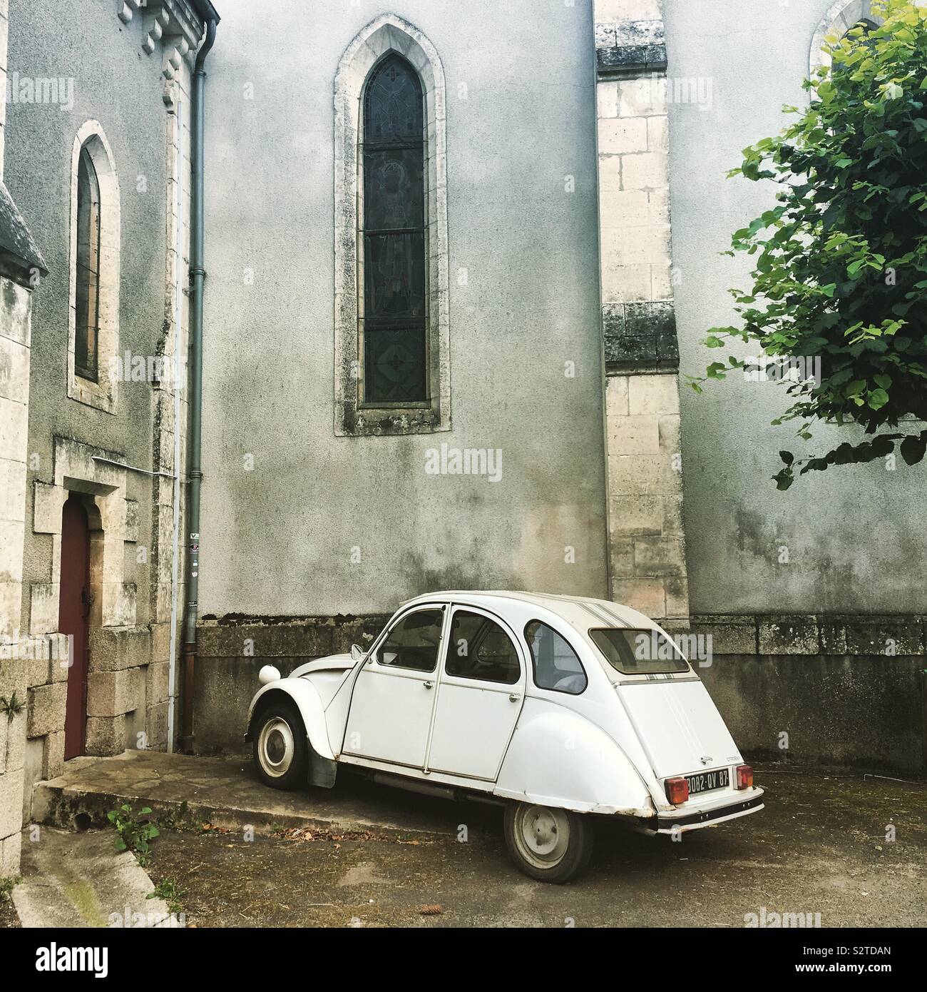 Un viejo blanco "deux chevaux" coche aparcado delante de una iglesia en una aldea francesa Foto de stock