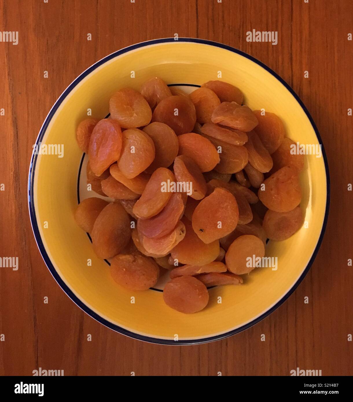 Los orejones en amarillo, blanco y azul plato colocado sobre una tabla de madera de teca. Foto de stock