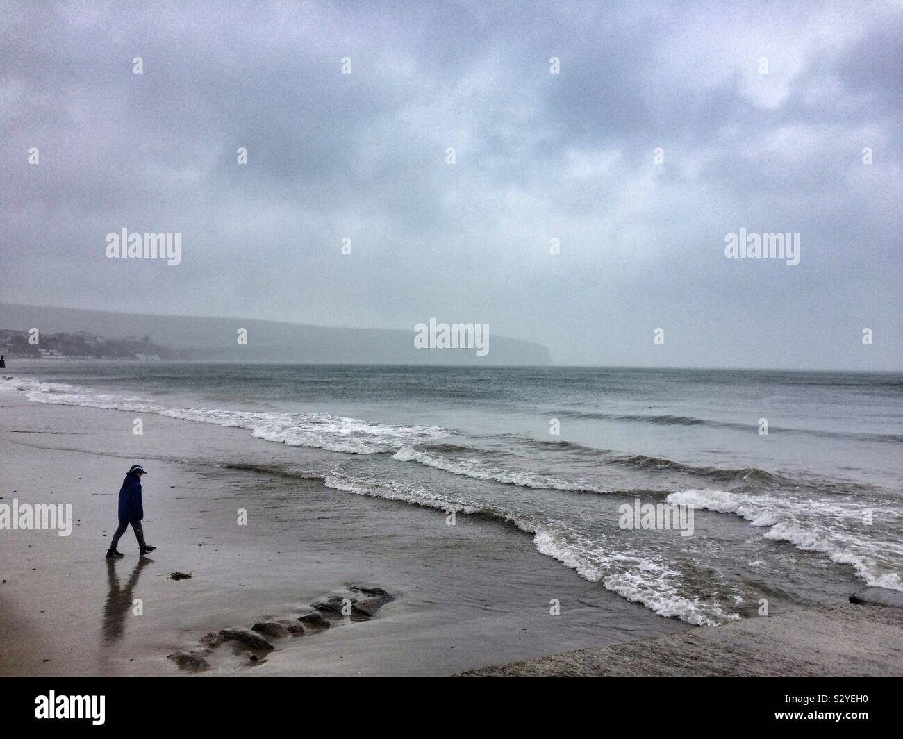 Un muchacho pasos hacia un sombrío invierno playa - Swanage, Reino Unido. Foto de stock