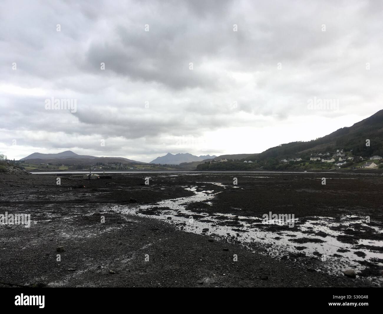 Marea baja sobre loch Portree, con las montañas Cuillin negro en la distancia, en Portree en la Isla de Skye Foto de stock