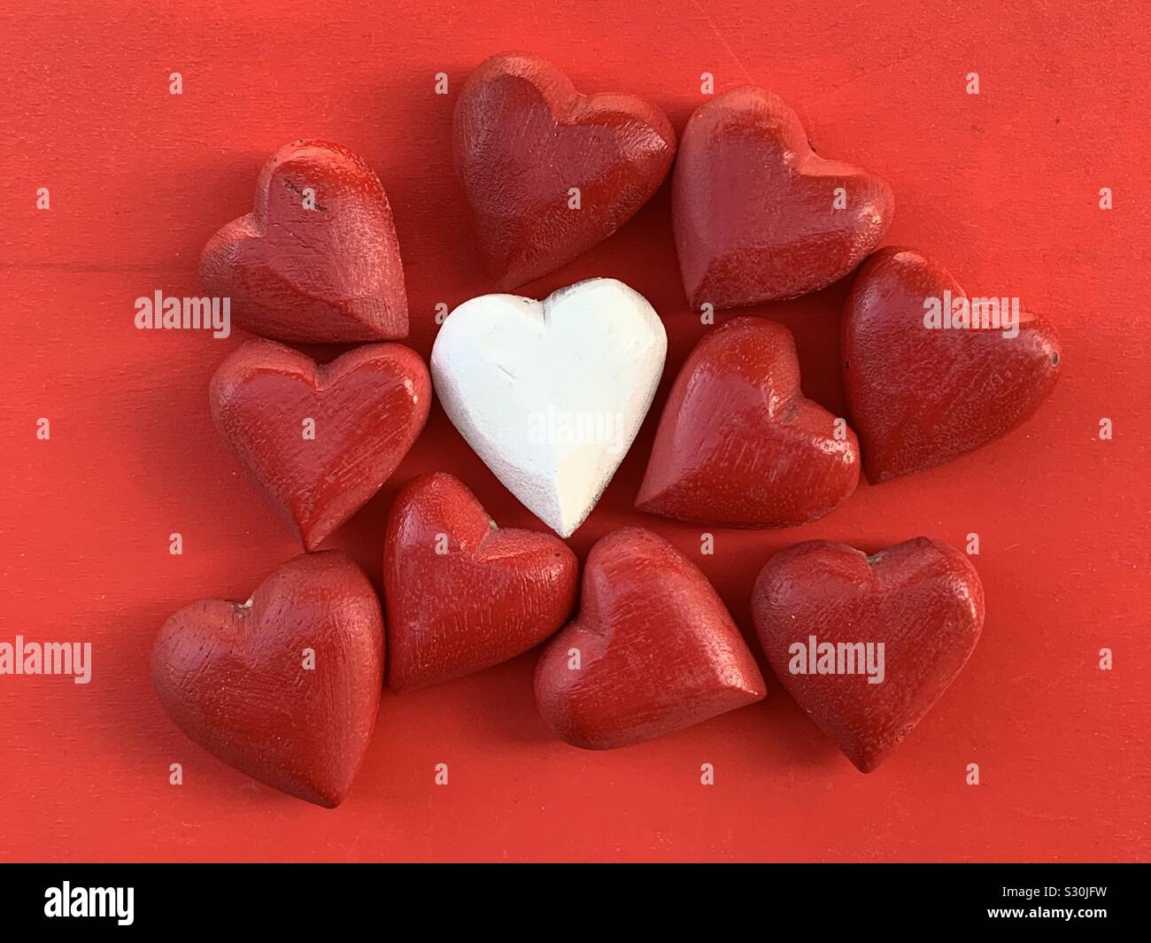 Amor diferente, conceptual y la composición creativa con corazones de madera roja alrededor de un núcleo blanco Foto de stock