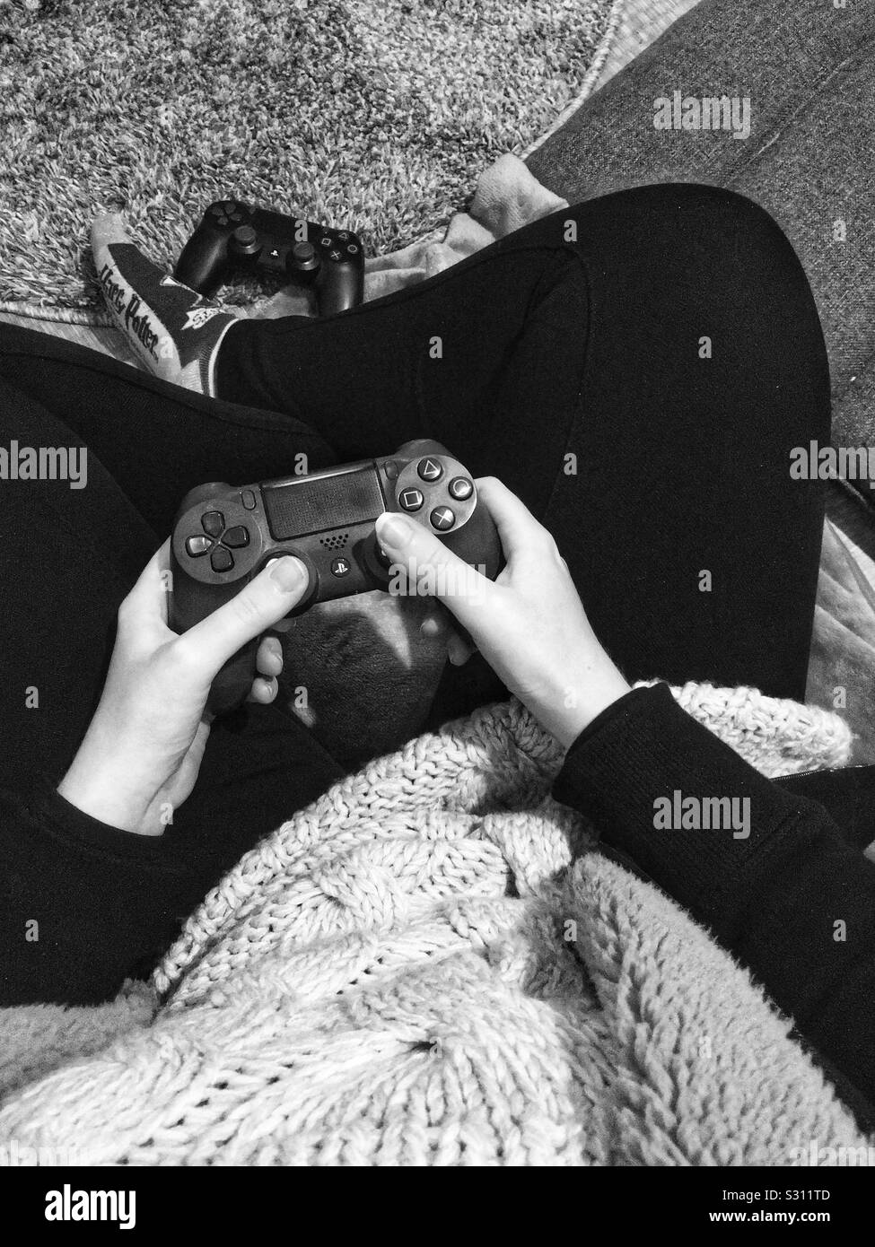 Mujer sentada en el suelo con un controlador de PlayStation Foto de stock