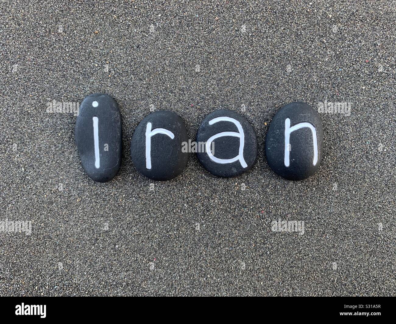 Irán, República Islámica del Irán, recuerdo con compuesto con letras de piedra de color negro a lo largo de arena volcánica negra Foto de stock